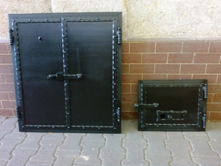 Tür zur Räucherei und zum Feuerraum, geschmiedete Profile und schwarze Matte.