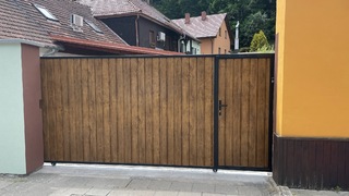 Schiebetor mit integriertem Tor, Konstruktion und Farbe aus Zink, Füllung aus „Blechholz“.